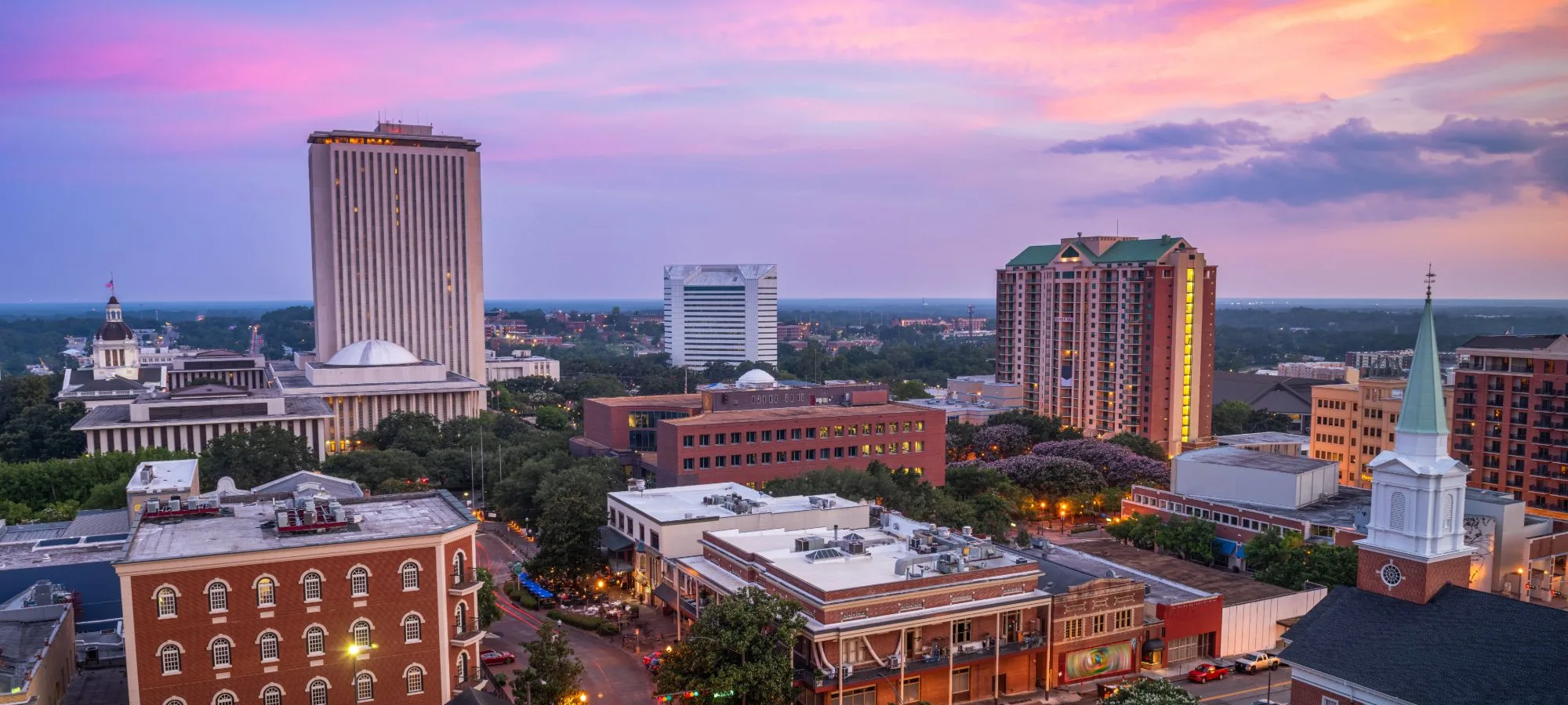Downtown Tallahassee skyline at sunset with the Florida State Capitol and historic brick buildings